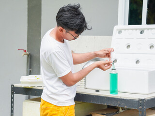 Asian man checking fertilizer vegetable hydroponics at home. People small business food farm. Healthy lifestyle crop ecology eco friendly for plantation and nutrition.