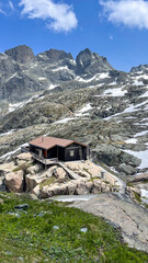 Remote Mountain Hut Nestled Among Rocky Alpine Peaks and Snow Patches