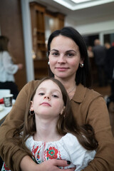 Vertical photo of affectionate middle aged mother and her daughter in vyshyvanka, emotional family bond concept
