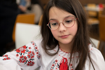Thoughtful sad schoolgirl in glasses sitting in classroom, loneliness emotion concept