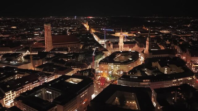 Hochwertige Drohnenaufnahme bei Nacht ueber Muenchen, Bayern, Blick auf Marienplatz, Neues Rathaus und beleuchtete Weihnachtsmaerkte im historischen Zentrum. Atmospheric winter night aerial of Munich