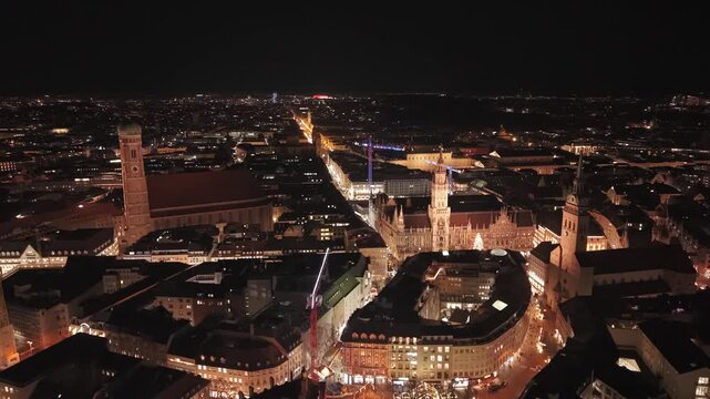 Atmosphaerische Winter Nachtaufnahme aus der Luft zeigt die Altstadt von Muenchen mit Stadtlichtern, Viktualienmarkt und historischen Wahrzeichen zur Weihnachtszeit. Night aerial view of Marienplatz