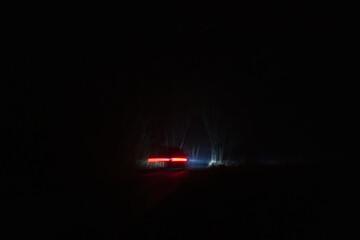 Car riding through forest on road with fog. Long exposure, brake light trail line, transport background