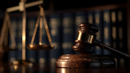 Close-up of a wooden gavel and scales of justice on a table in a dimly lit legal environment, symbolizing law and order