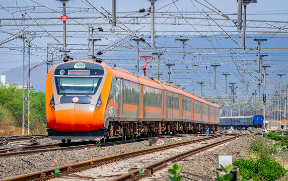 India's first indigenous development semi high speed orange Vande Bharat express , also known as train 18 , exits a wayside station.