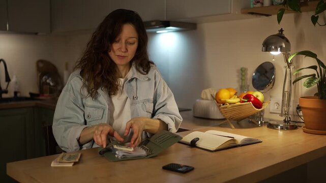 Frugal housewife distributing cash into a budget binder for savings, expenses, and utility bill payments, practicing a cash stuffing method for financial planning and accounting at home