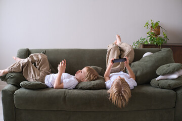 kids boys twins using smartphones lying on the couch