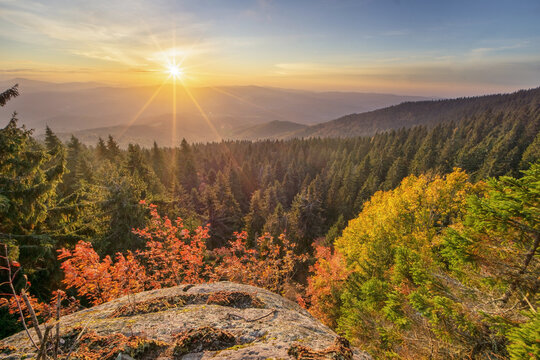 View of the sun bursts forth, illuminating the vibrant autumn foliage blanketing the rolling hills and dense forests, Polana, Banska Bystrica Region, Slovakia.