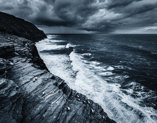Dramatic coastal cliffs meet a wild, tempestuous sea under a foreboding sky, evoking natures raw power.