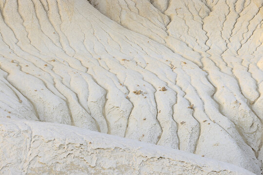 View of the earth's crust, a textured landscape with deep grooves and soft white color, shaped by time, in Senek, Mangystau Region, Kazakhstan.