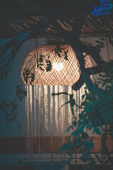 Elegant Wicker Pendant Light with Crystal Beads Hanging Under a Tree at Night