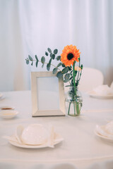 Vertical Wedding Table Mockup with Blank Frame and Orange Gerbera in Glass Vase