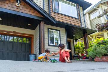 Mother and son playing with dinosaur toys in front of house