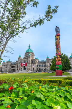 Totem pole standing tall in front of parliament buildings in victoria, british columbia