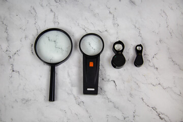 Magnifiers magnifying lenses of various sizes on a gray marble table. Tools, construction, production, design, structures.