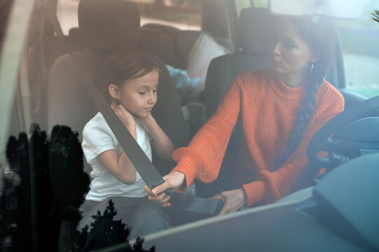Mother securing child in car with seatbelt