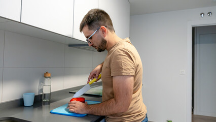 Man cutting red pepper in home kitchen