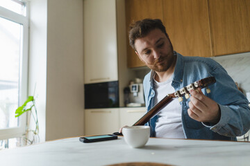 Young man casually playing guitar in cozy setting