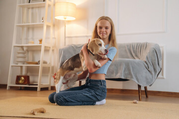 Casual time spending, wellness. Girl is with her dog on the floor in a cozy living room