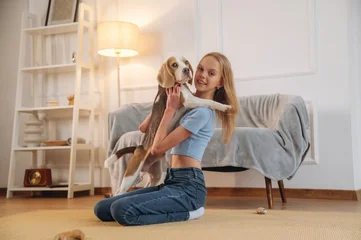 Fotobehang Ridders Side view, sitting. Girl is with her dog on the floor in a cozy living room  © standret