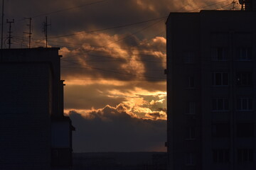 Sunset over the city. The rays of the sun break through the clouds