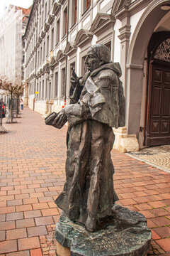 Bronze statue of a historical monk figure on a quiet street with classical European architecture in the background, editorial use only. Photo taken 30 November 2025 Dillingen, Bavaria, Germany
