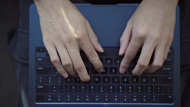 Top-Down Cinematic Shot of a Person Typing on a Laptop. A cinematic top-down shot of a person typing on a laptop at a clean, minimalist workspace.