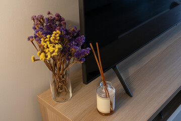 Dried flowers and reed diffuser on a wooden TV stand cozy evening living room, warm evening light