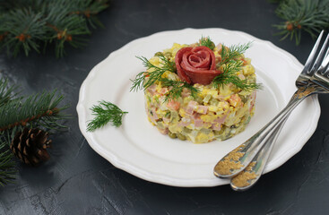 Homemade salad Olivier with sausage, peas and potatoes on white plate on gray background