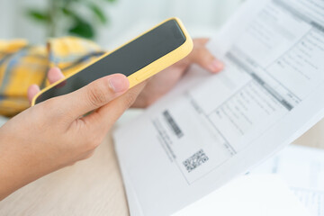 woman use phone scan barcode or QR codes to pay credit card bill after receiving document invoice. payment, receive, paying electricity, digital payments, technology, scanning, financial transactions