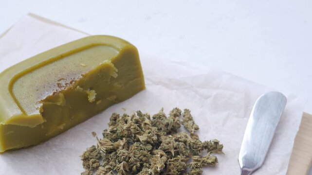 Close up shot of cannabis-infused butter (cannabutter) and a spatula on parchment paper, medicinal and edible marijuana concept.