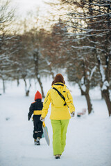 Mother and son walking in snowy winter park