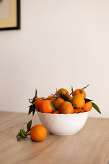 Full bowl of fresh tangerine on a wooden table.