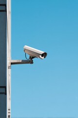 Outdoor surveillance camera mounted on building against clear blue sky