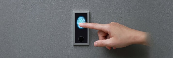 Hand pressing fingerprint scanner on gray wall for secure access