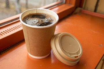 Brown Paper Coffee Cup with Beige Lid on Orange Surface