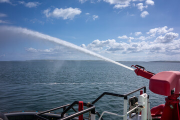 Firefighting Water Cannon Spraying Over Open Sea from Vessel. Maritime Safety, Emergency Response, and Marine Equipment Demonstration
