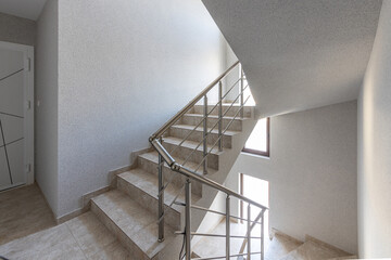 Modern stair case between floors. Stairs with metallic rail in modern building. Interior of a contemporary apartment or office building. Architecture and real estate background.