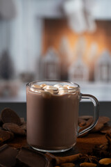 Warm drink with marshmallows and chocolate pieces near a cozy fireplace setting during winter evening