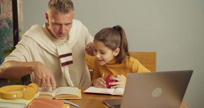 Father and daughter practicing math with coins at dining table