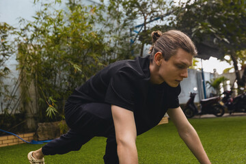 Naklejka premium Young caucasian male preparing for outdoor exercise in green park setting