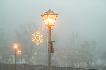 Neckarbr&uuml;cke in Neckartenzlingen mit weihnachtlicher Beleuchtung in Form von Schneeflocken im Nebel 