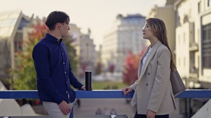 Young business professionals engage in a focused discussion on a city bridge, exchanging ideas and plans in an urban environment.