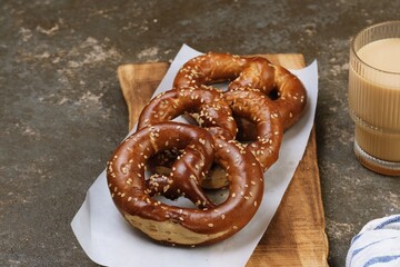 Freshly baked soft pretzels topped with sesame seeds, served on a wooden board with rustic food styling.