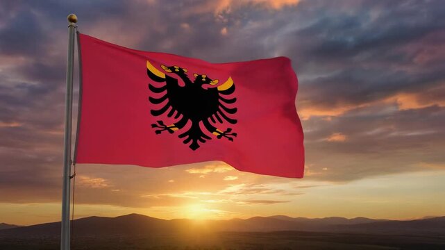 Vibrant Albanian flag with black double-headed eagle waving against a dramatic sunset and mountain landscape representing national pride and heritage