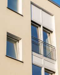 Modern apartment building features large windows and a small balcony in bright light
