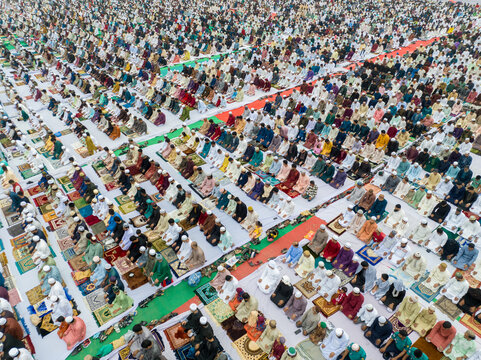 Aerial view of a large gathering of people praying outdoors, their colorful prayer mats creating a vibrant mosaic on the ground, Dhaka, Dhaka Division, Bangladesh.