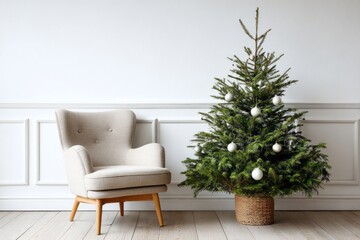 Simple decorated evergreen stands beside a comfortable armchair against a paneled white wall