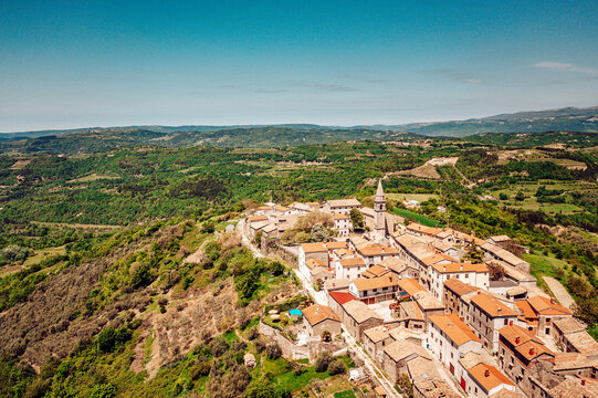 Aerial view of terracotta rooftops cascade towards the Adriatic, embraced by the lush green hills and the iconic steeple of the church, Primosten, Sibenik-Knin County, Croatia.