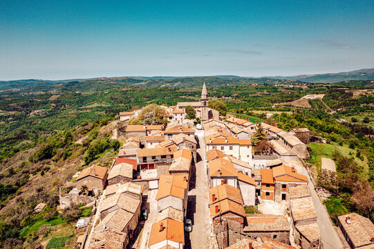 Aerial view of terracotta rooftops cascade down to meet the Adriatic in a symphony of color and light, punctuated by the church tower, Primosten, Sibenik-Knin County, Croatia.